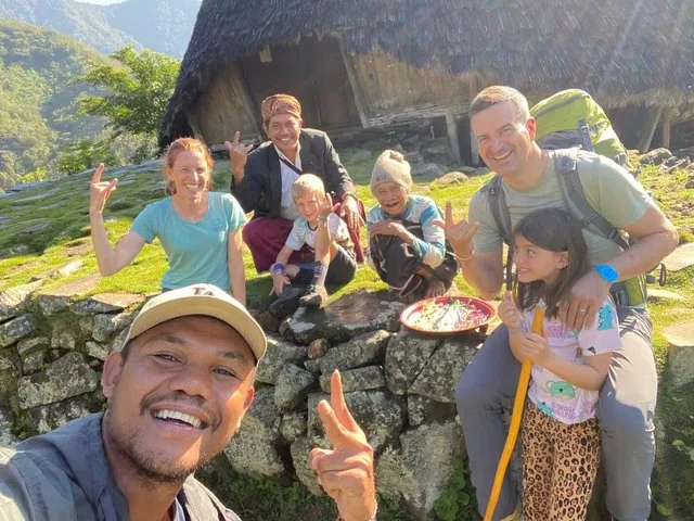 Un gruppo di turisti che si scatta un selfie con gli abitanti del villaggio a Wae Rebo.